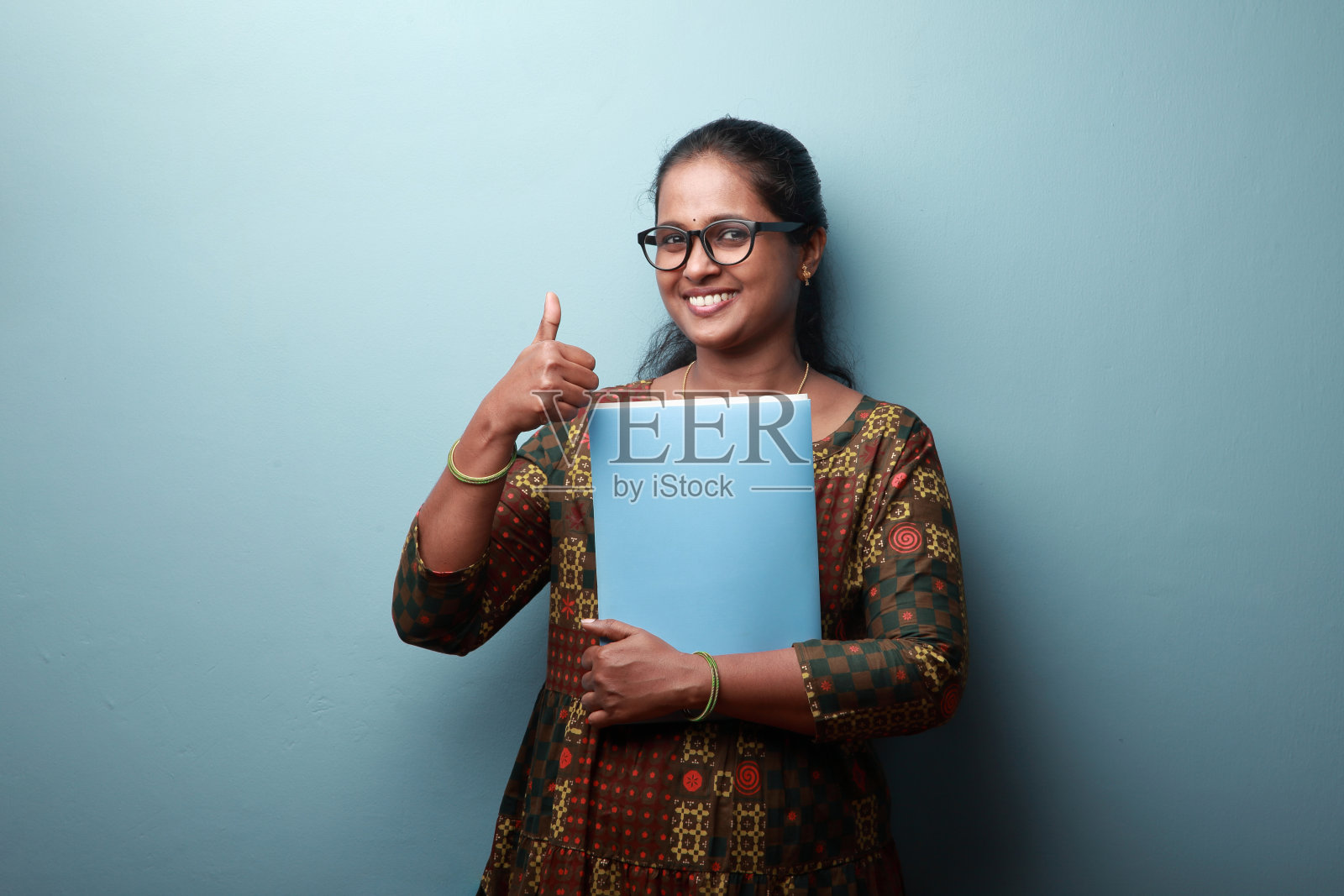 微笑的印度裔妇女拿着文件，竖起大拇指照片摄影图片