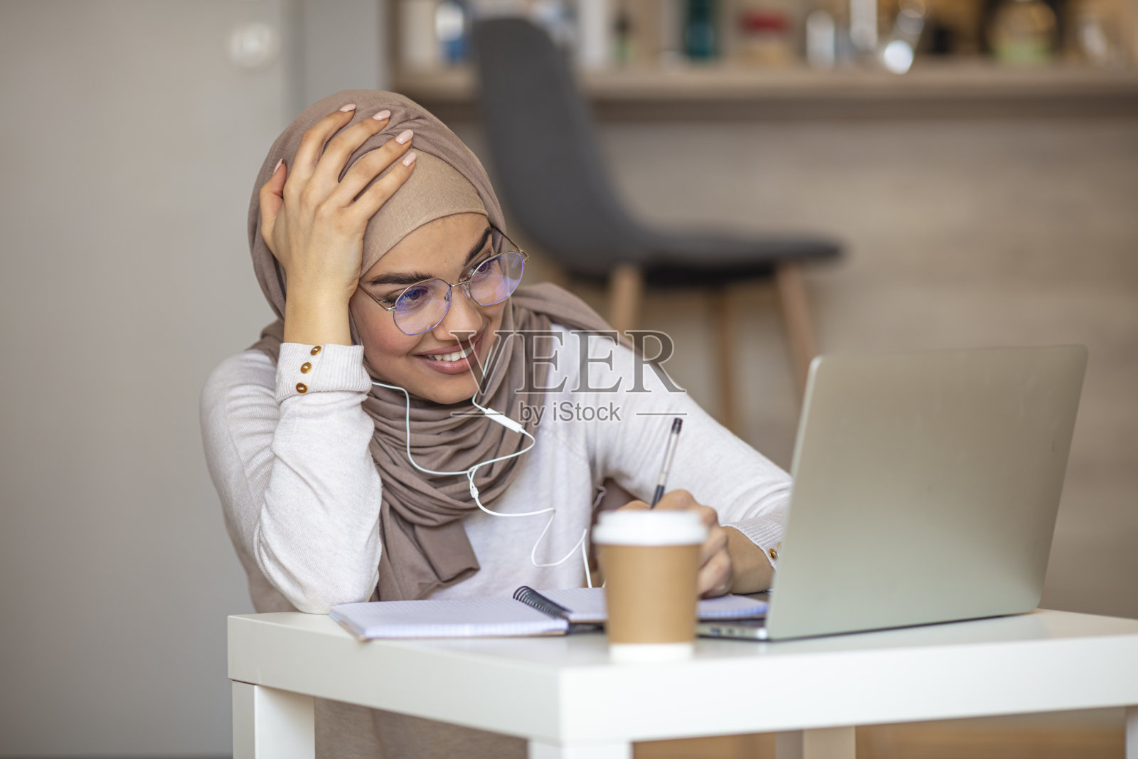 一个戴着头巾的年轻女子正在家里开视频会议照片摄影图片