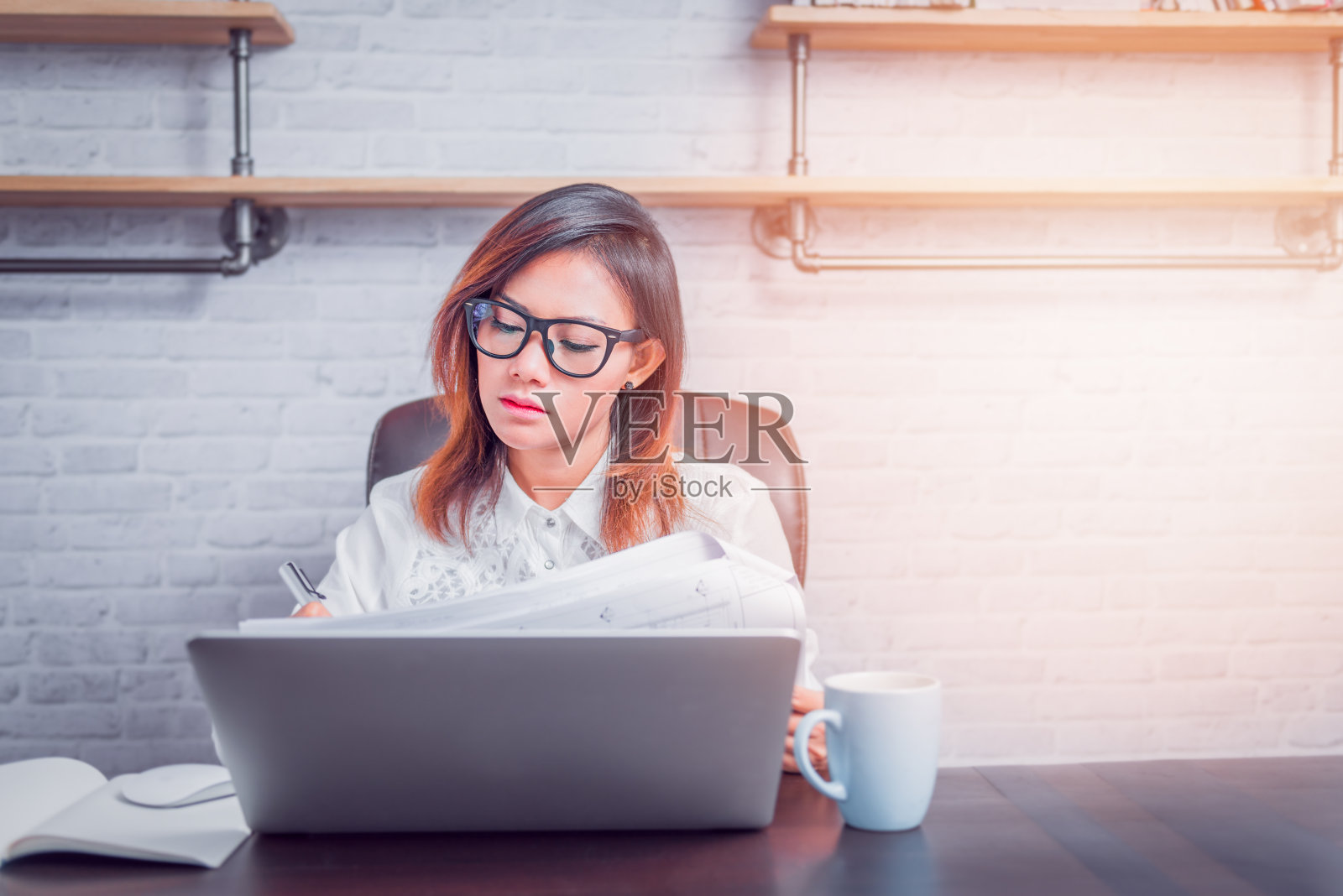 有工作的亚洲女人坐在家里，有意向。关注的脸。照片摄影图片