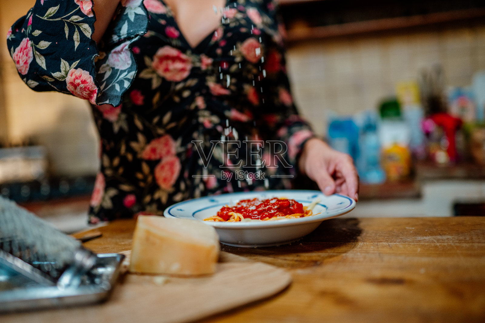 一位女士在意大利面上撒奶酪照片摄影图片