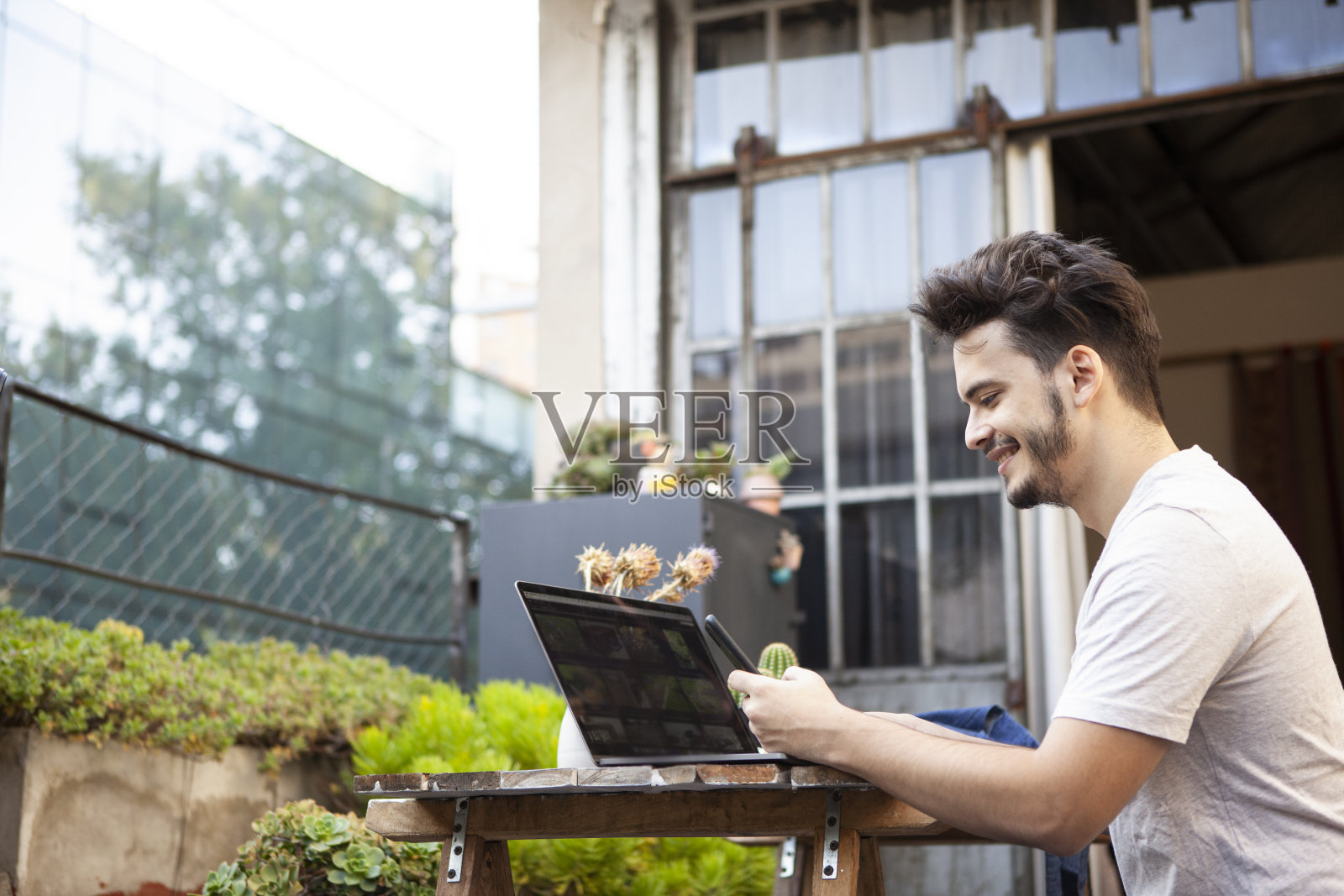 侧面的年轻企业家坐在花园的桌子上工作在白天的笔记本电脑照片摄影图片
