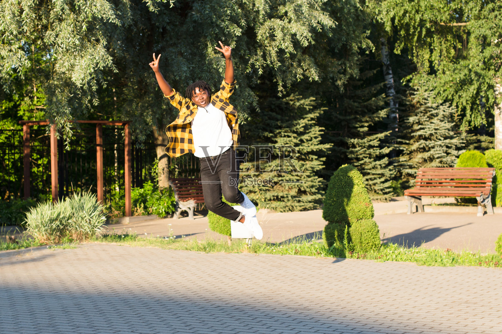 一个快乐的非裔美国妇女在夏天在公园里跳跃照片摄影图片