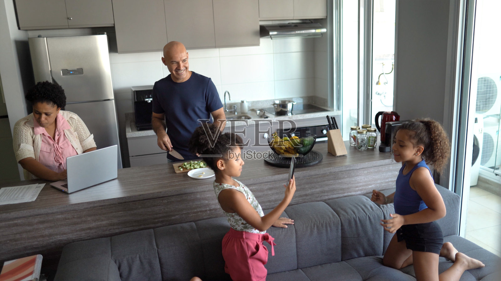 当父母在家工作和做饭时，女孩们在拍摄照片摄影图片