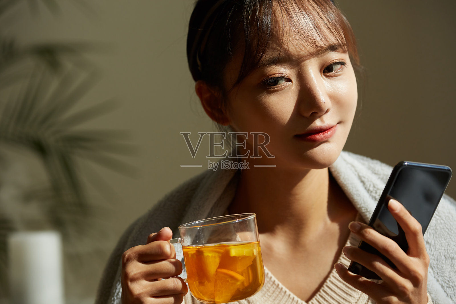 一个年轻的亚洲女人在家里喝水果茶放松照片摄影图片