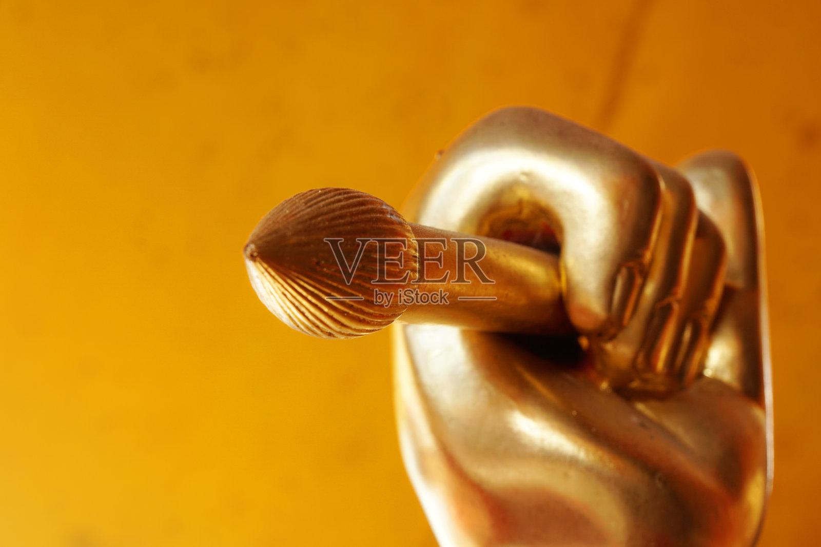 金色手和画笔雕像特写，黄色墙壁背景照片摄影图片