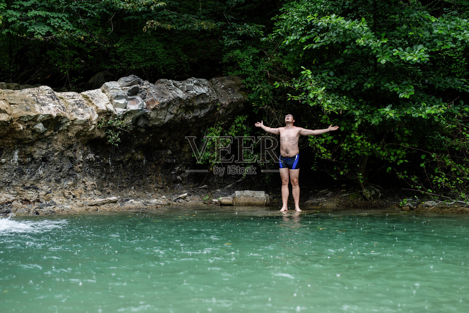 男人在有瀑布的山间河流里游泳照片摄影图片