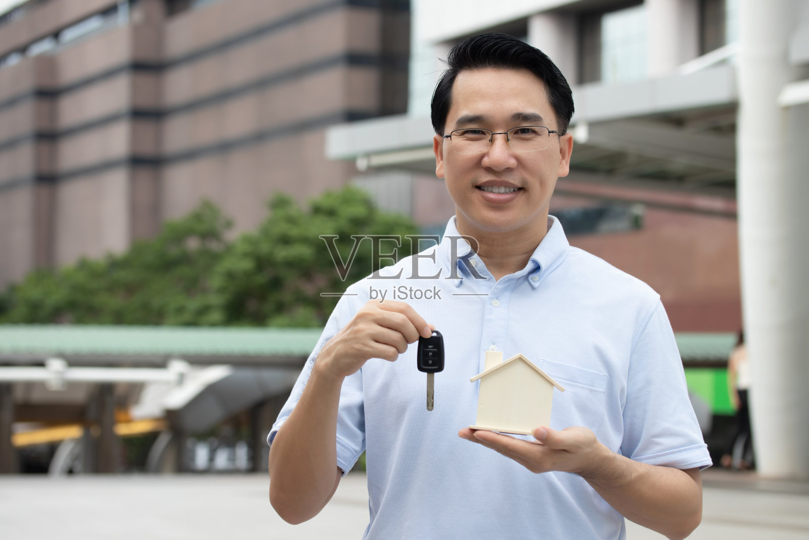 商人持有模型房子和汽车钥匙，为未来存钱，维修家园和退休。商业贷款适用于房地产和汽车租赁概念。照片摄影图片