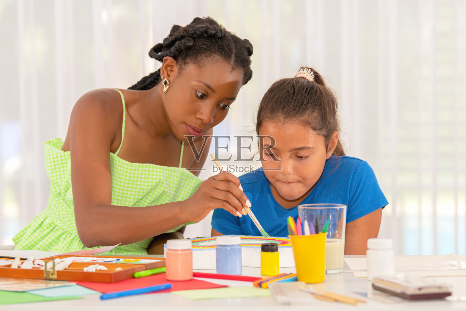非裔美国老师在美术课上帮助拉丁女学生画画照片摄影图片
