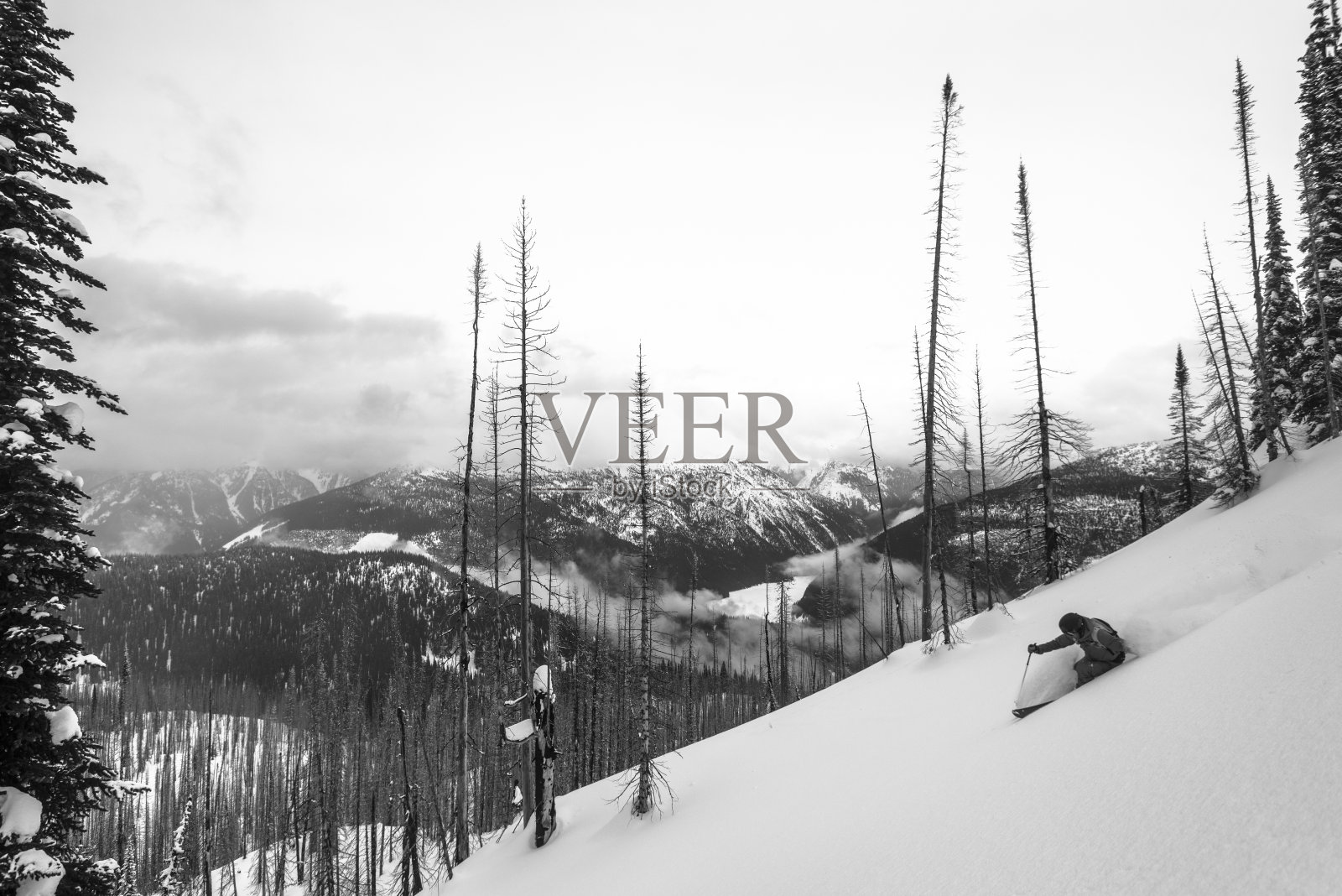 偏远地区的滑雪者从雪山山脊上滑下来照片摄影图片