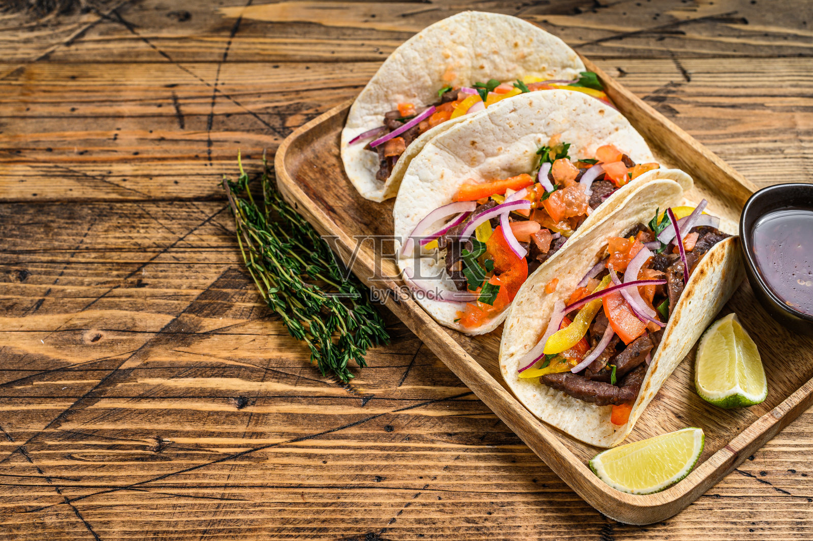 玉米饼里面有牛肉，洋葱，西红柿，甜椒和莎莎酱。墨西哥食物。木制背景。前视图。本空间照片摄影图片