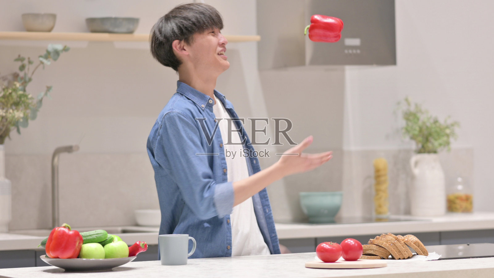 年轻的亚洲人在厨房里玩蔬菜和跳舞照片摄影图片