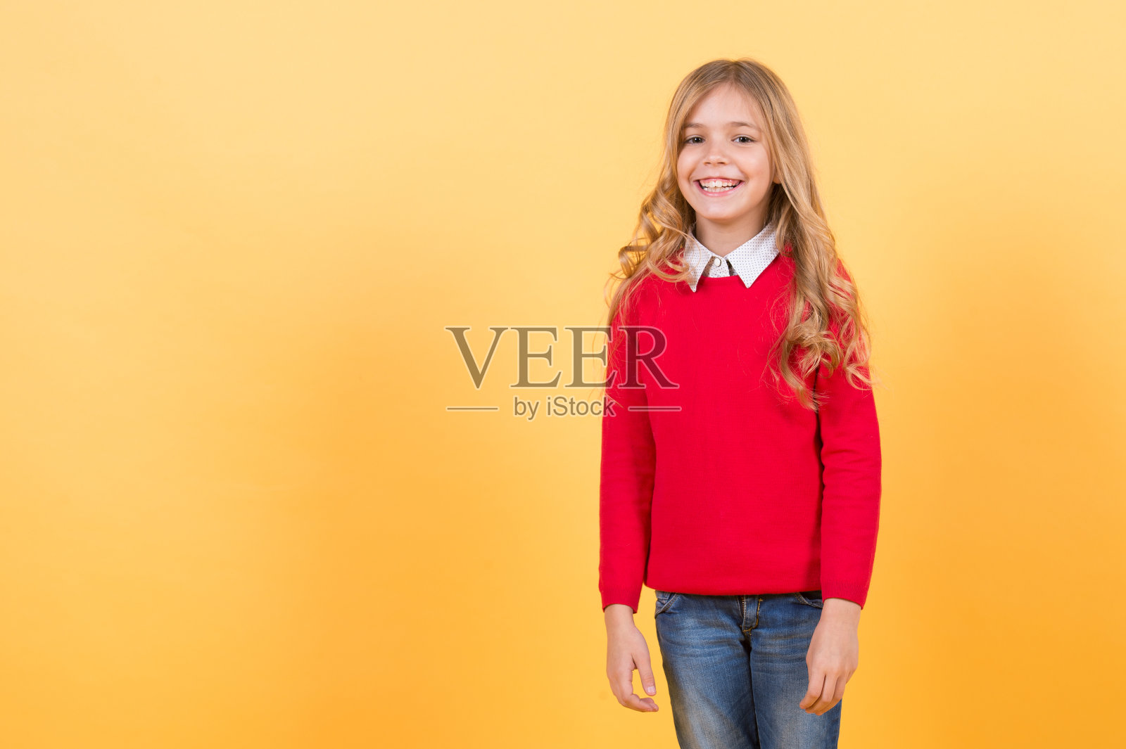 孩子长着金色长发，穿着红色毛衣，开心地笑着照片摄影图片