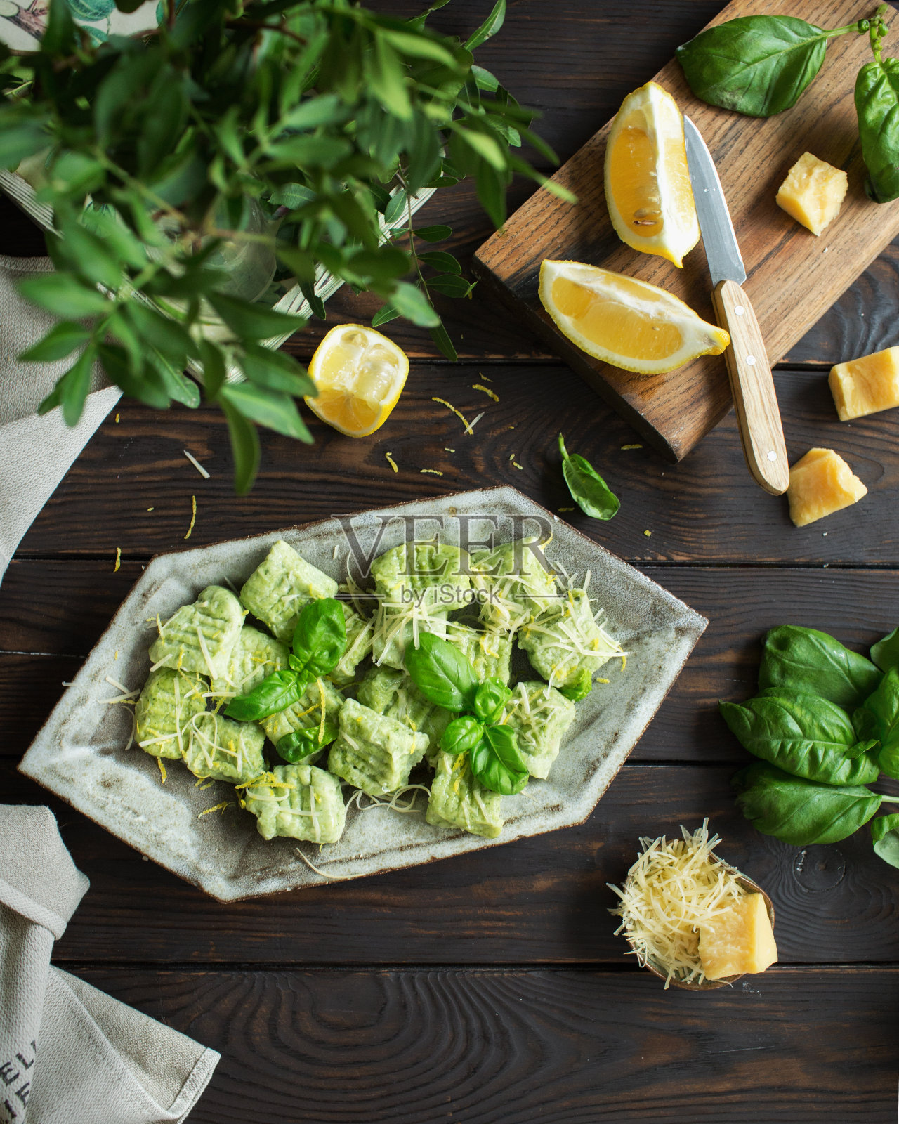 意大利菜。罗勒汤圆配帕尔马干酪和柠檬汁。绿色的健康食品放在棕色的木制背景上。照片摄影图片