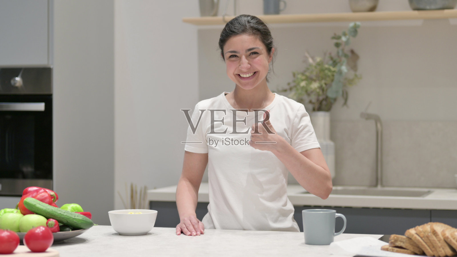 印度年轻女子站在厨房竖起大拇指照片摄影图片