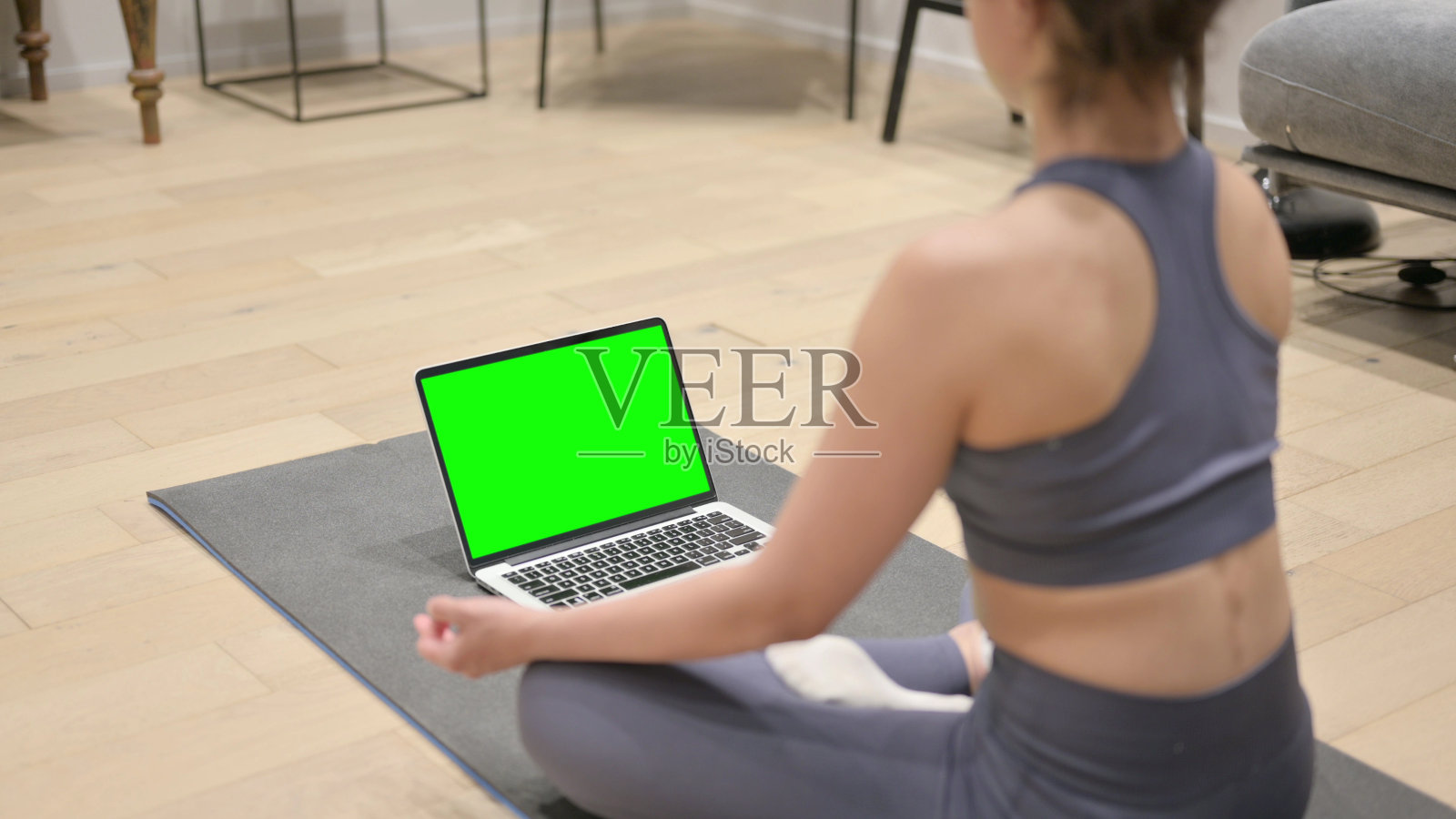 印度女人在瑜伽垫上使用带有彩色屏幕的笔记本电脑的后视图照片摄影图片