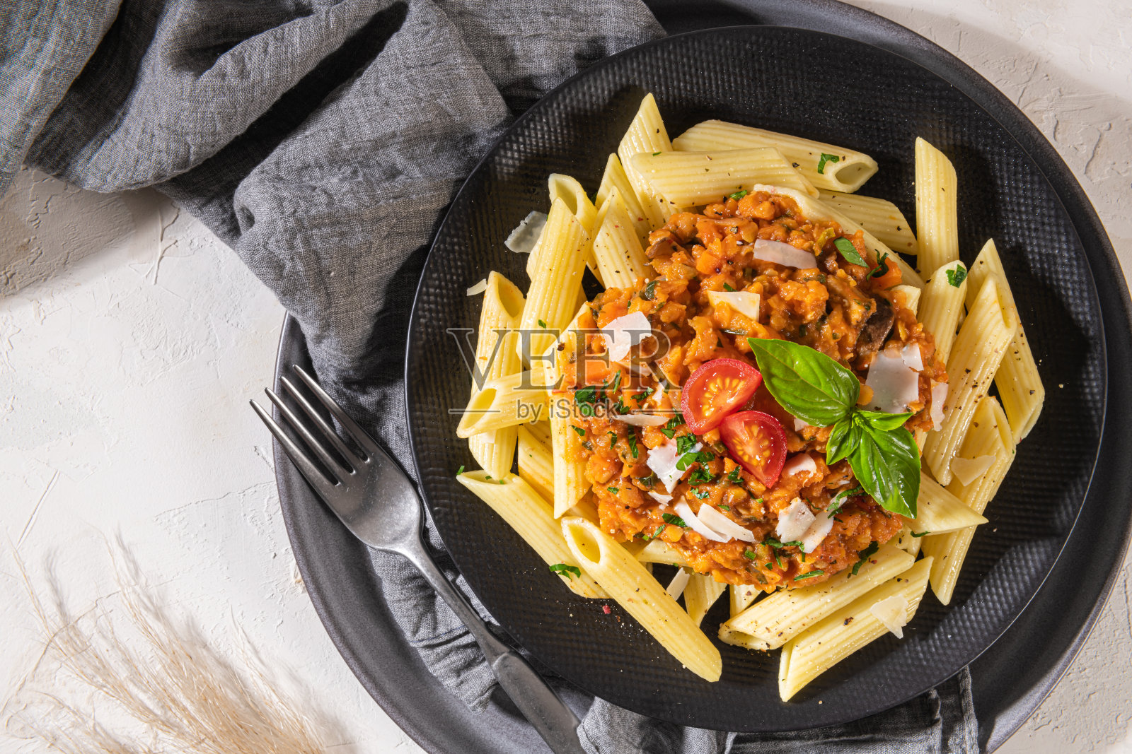 美味可口的经典意大利通心粉，配素食扁豆肉酱，芝士帕尔马干酪和罗勒。健康饮食的概念。照片摄影图片