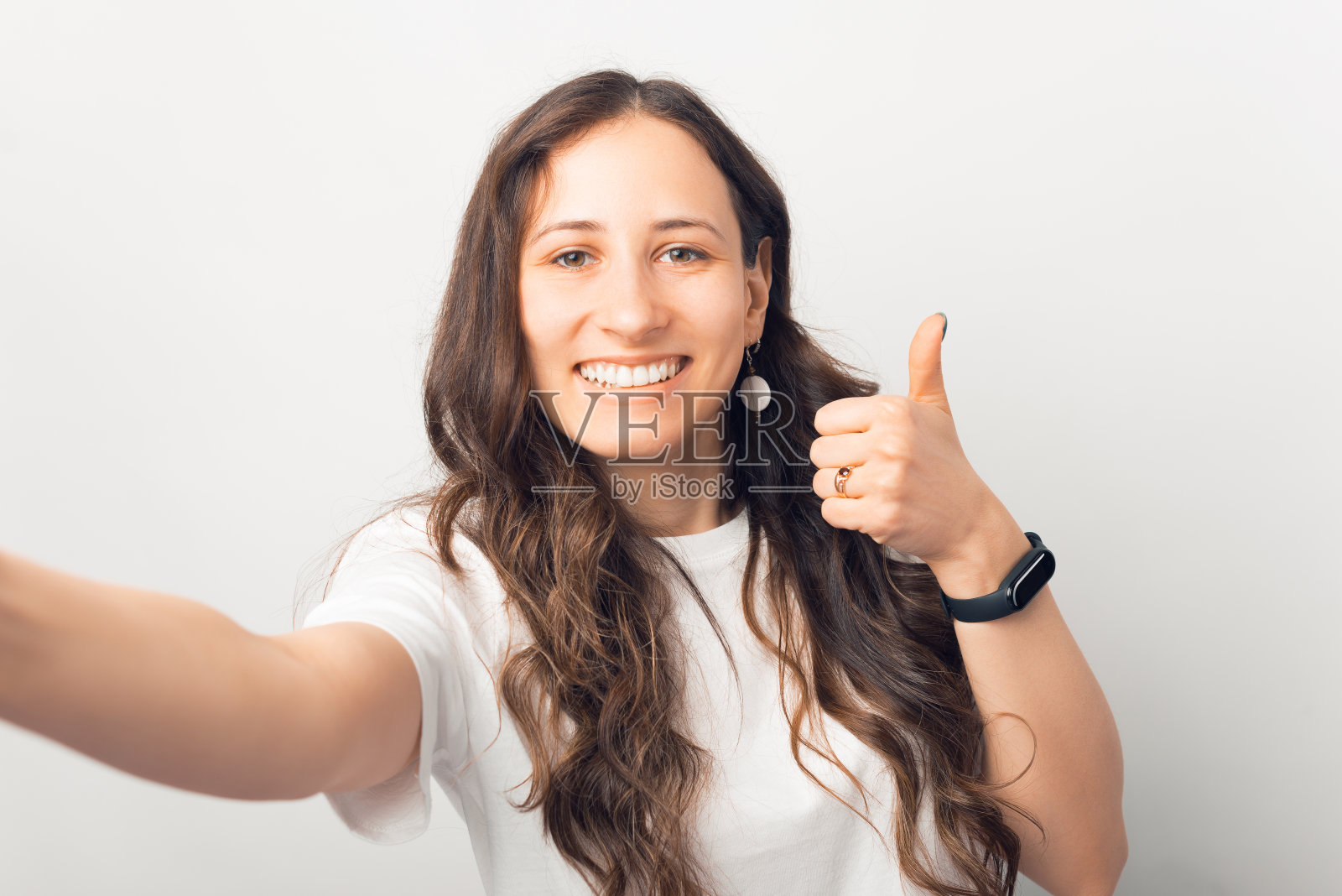 一张照片上，一个快乐的小女孩看着相机，竖起大拇指，微笑着照片摄影图片