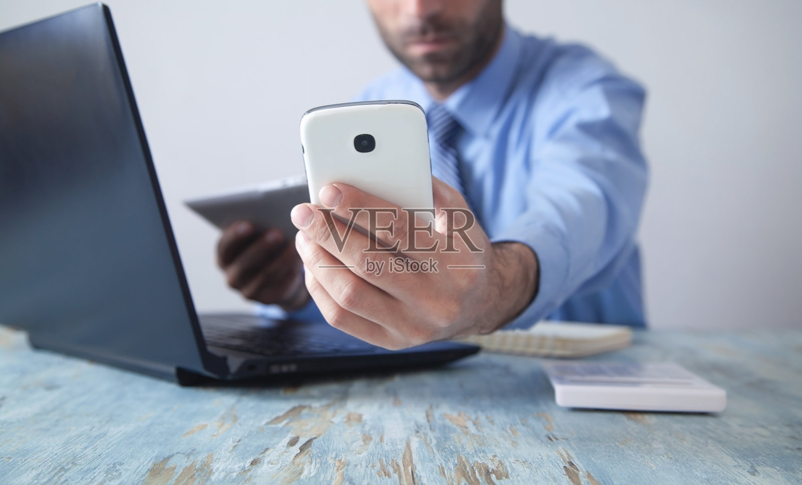 使用智能手机在办公室工作的商人。照片摄影图片