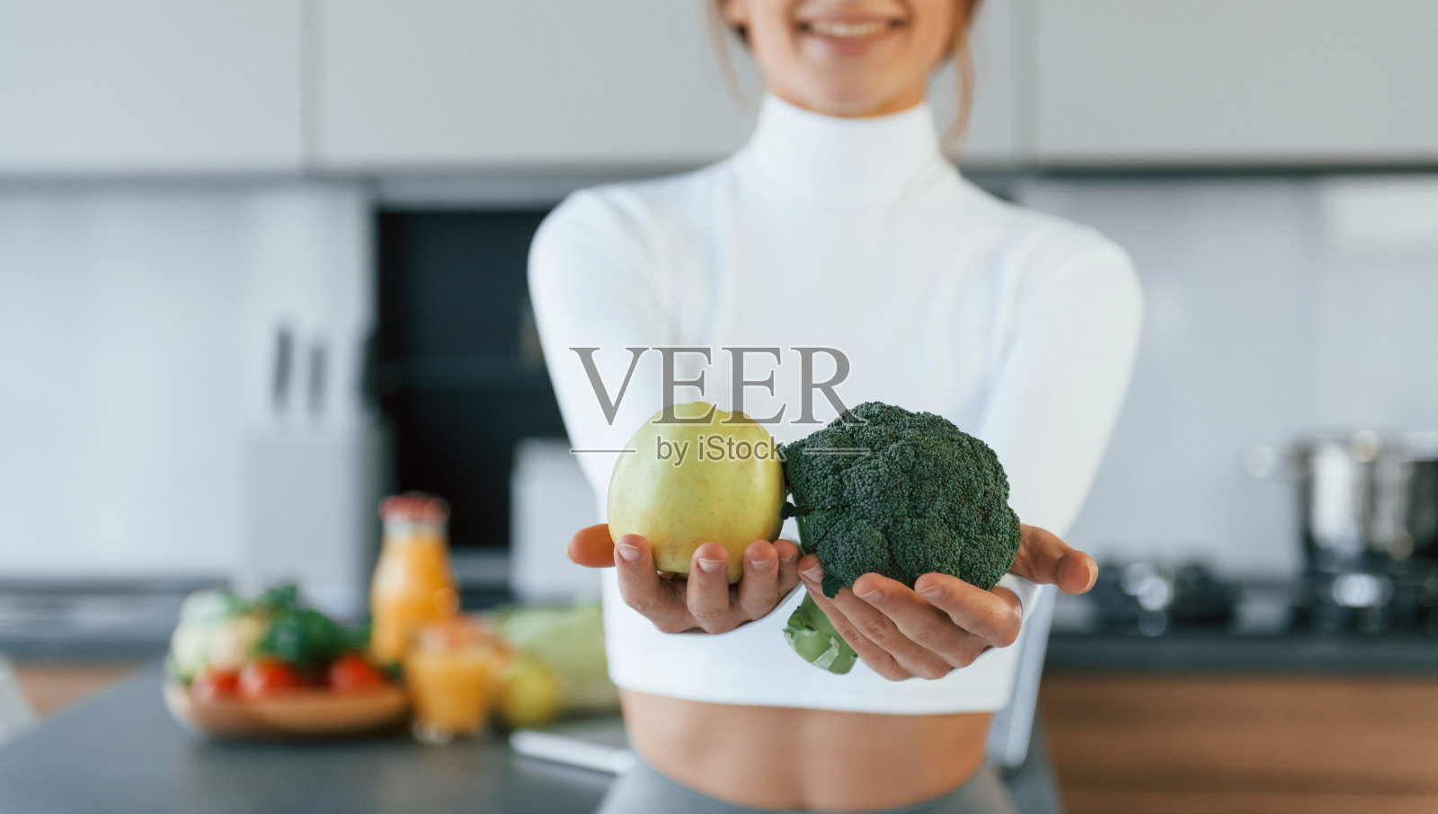 拿着蔬菜摆姿势照相。年轻的欧洲妇女在厨房里吃着健康的食物照片摄影图片