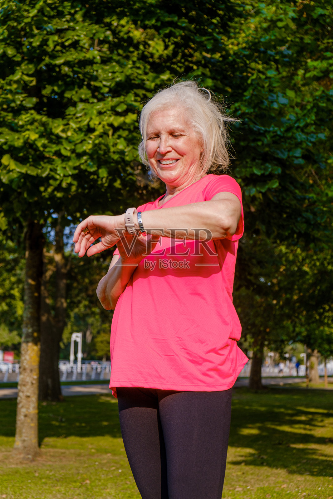 在公园训练期间检查她的智能手表的运动妇女的肖像。照片摄影图片