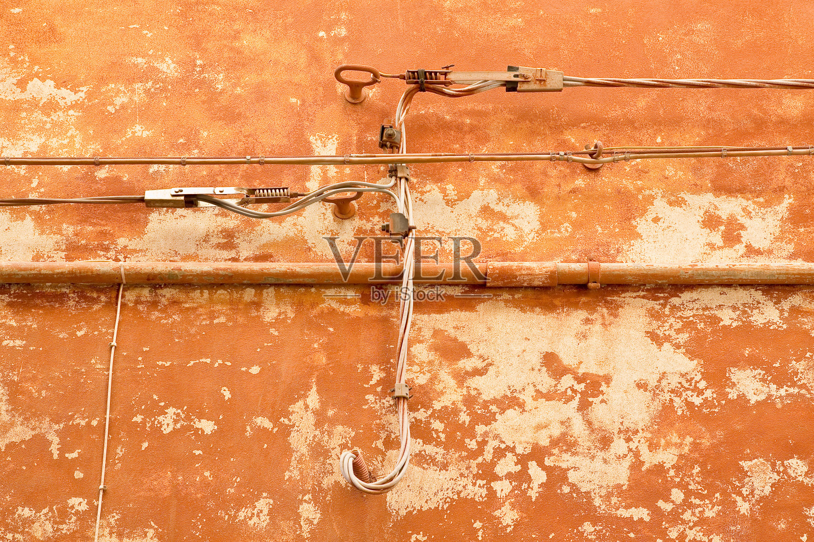 电力电缆和电话电缆靠在旧砖墙和灰泥墙上，用于配电。照片摄影图片