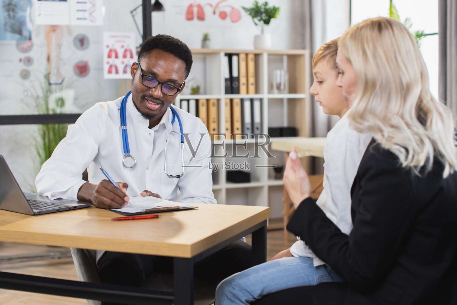 母亲带着儿子去现代诊所看儿科医生照片摄影图片