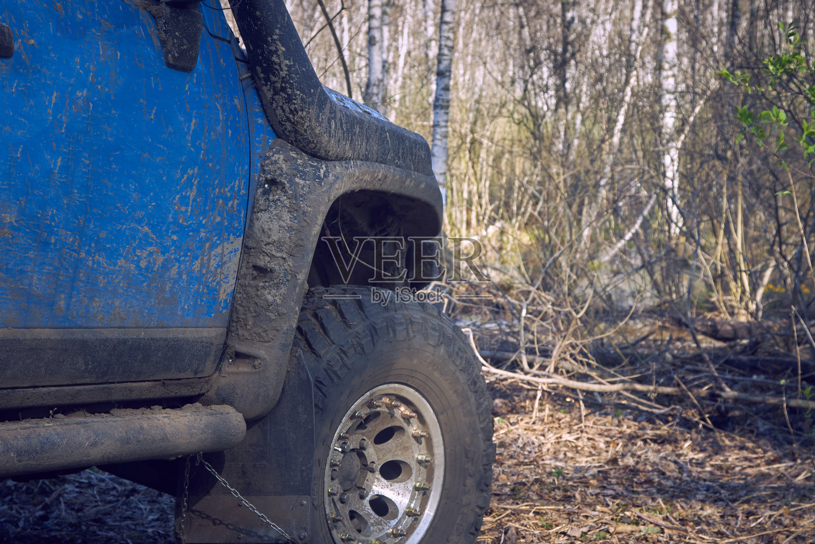 在森林路上开一辆蓝色的4x4汽车。照片摄影图片