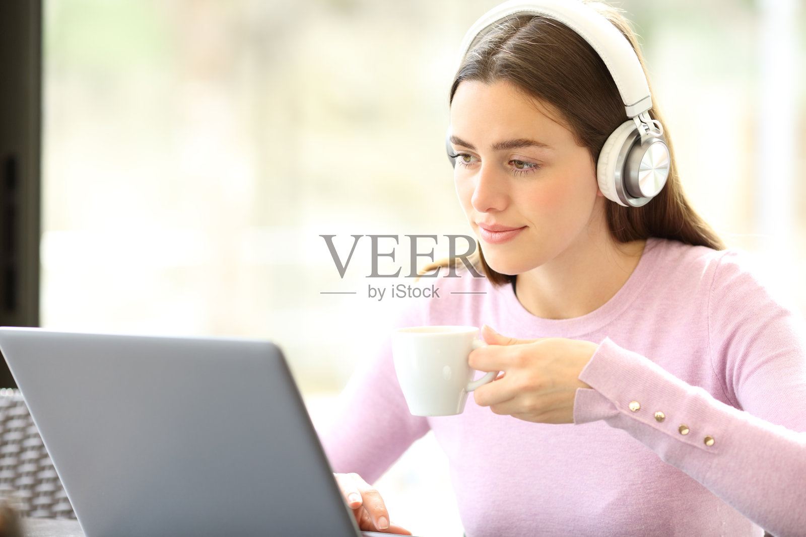 轻松的女人使用笔记本电脑和耳机喝咖啡照片摄影图片