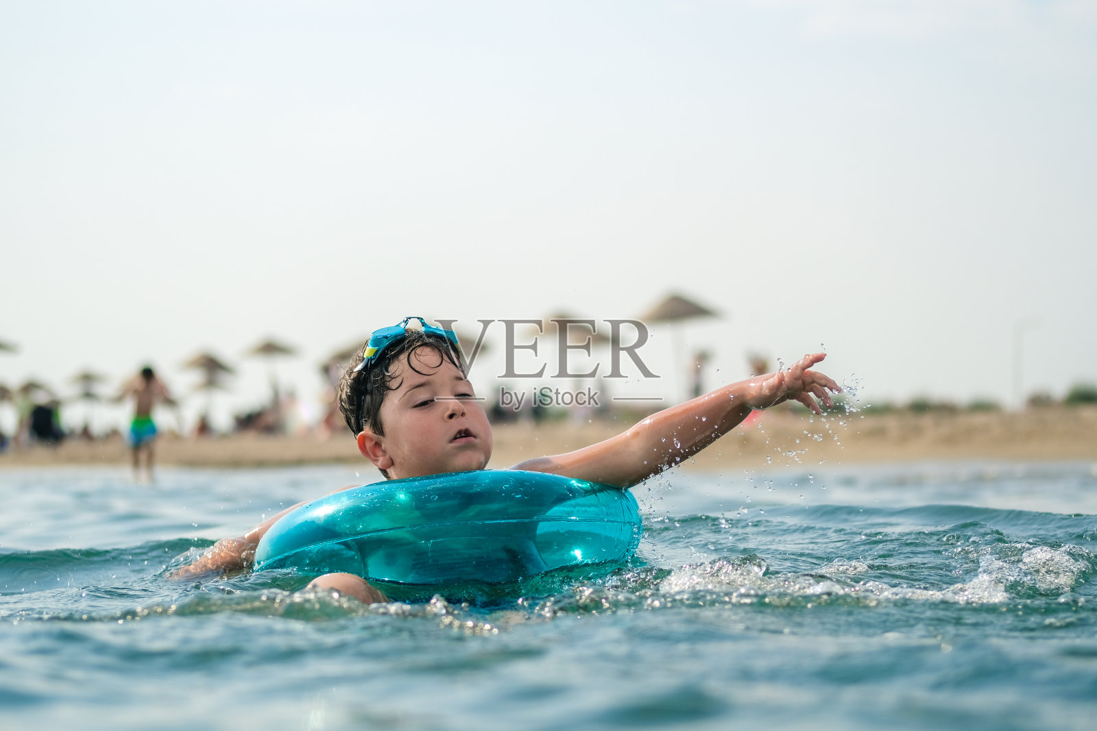 快乐的男孩喜欢用橡皮圈在海里游泳。学习游泳照片摄影图片