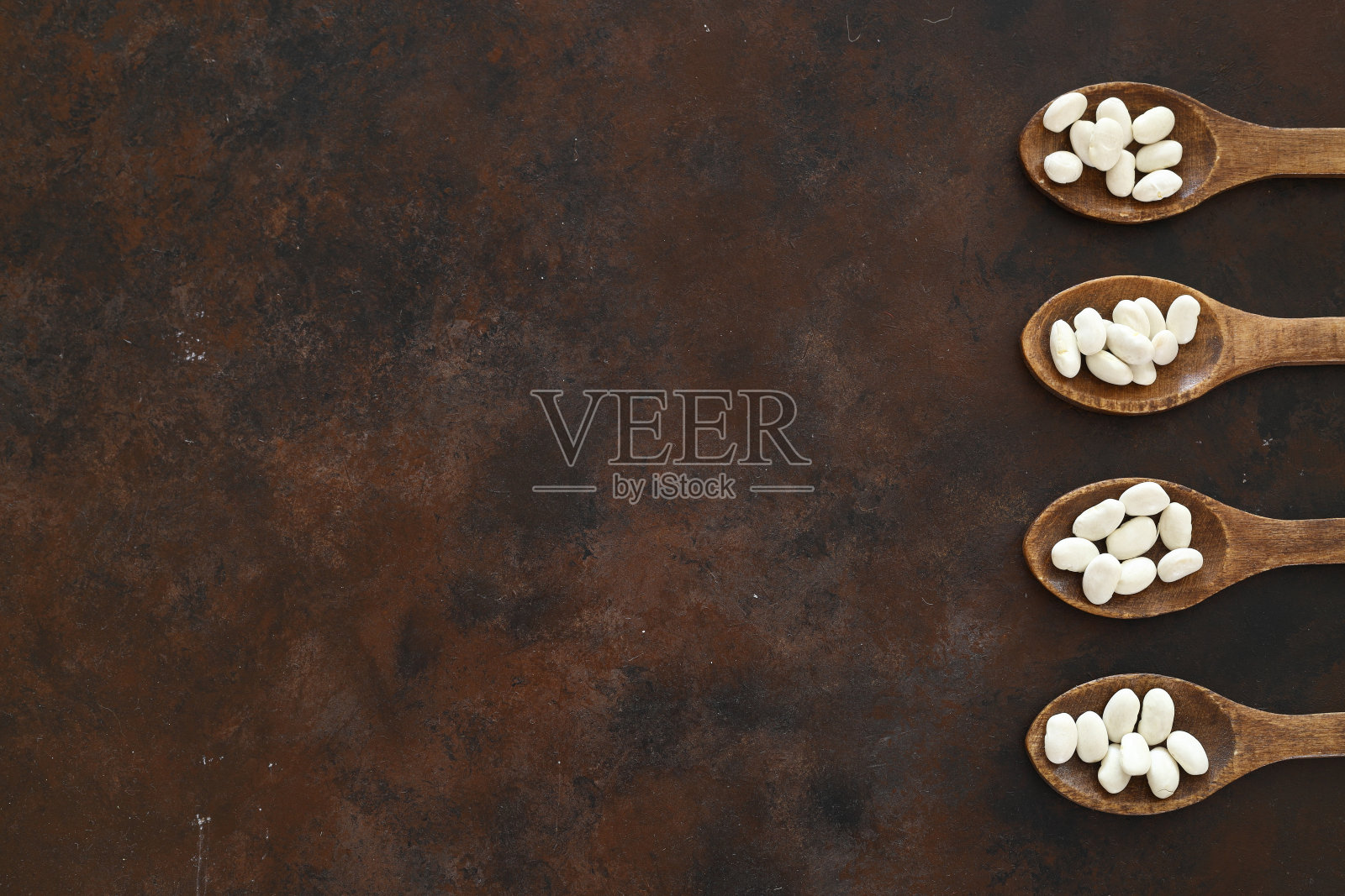 白色芸豆在木勺孤立在木制背景。前视图。平躺照片摄影图片