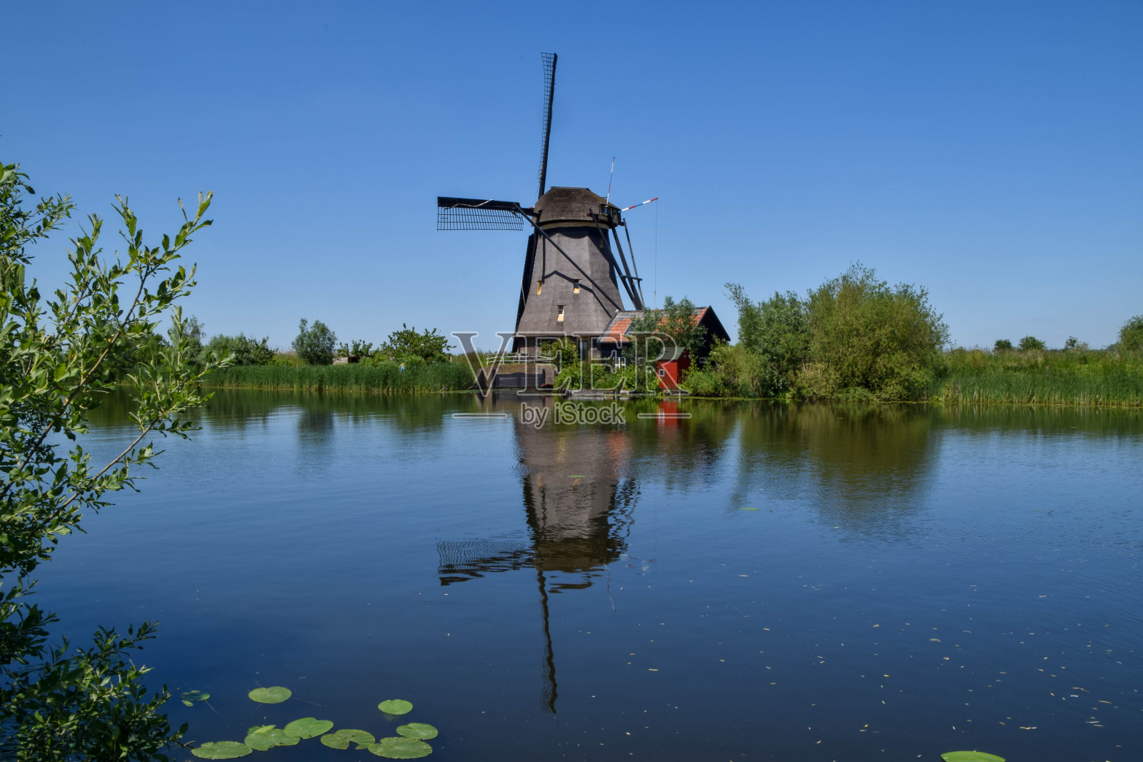 典型的荷兰景观，在阿尔伯拉斯瓦尔德的金德代克(Kinderdijk)的圩田中，有一座经典的风车，沿着水面倒影美丽照片摄影图片