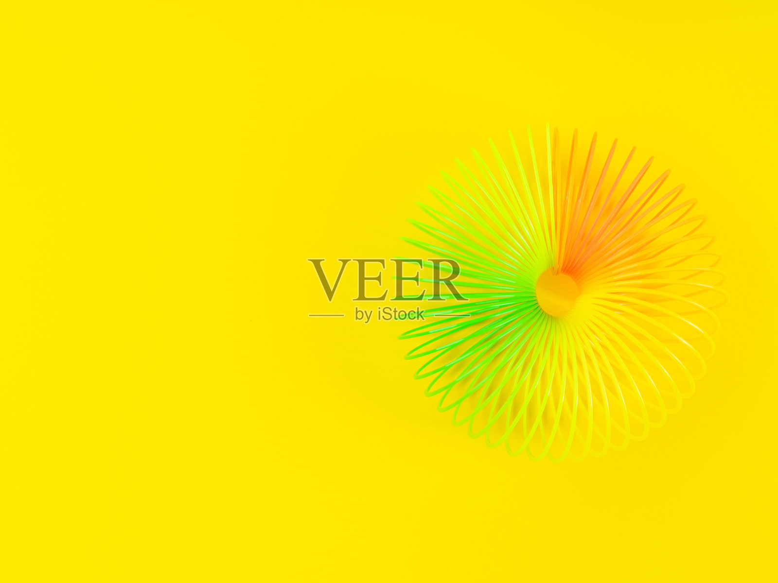 彩色彩虹螺旋塑料玩具的黄色背景照片摄影图片