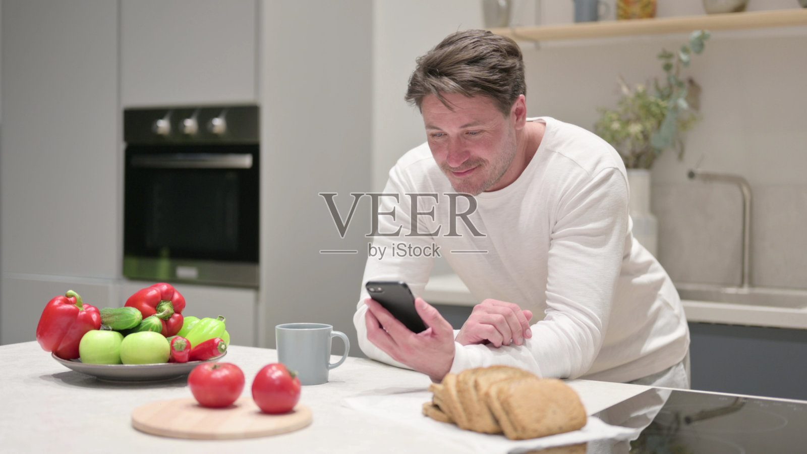 中年男子在厨房里使用智能手机照片摄影图片