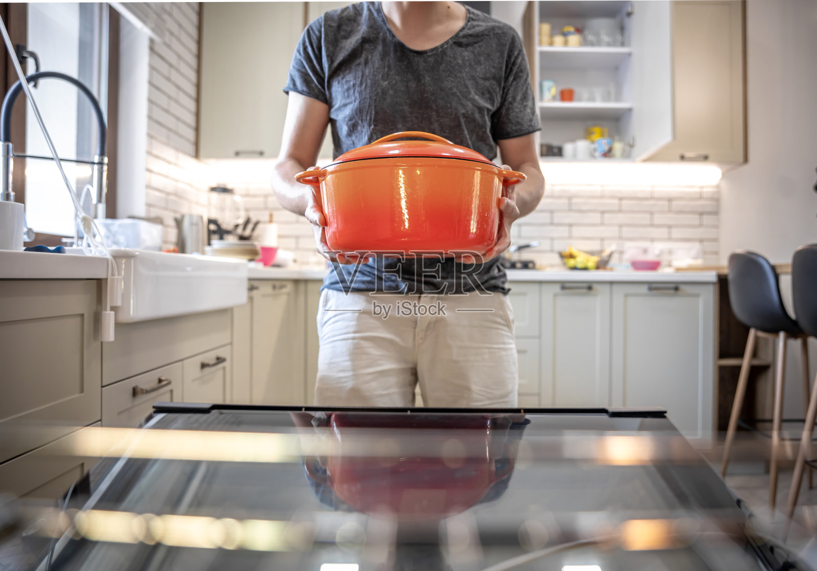 一个男人手里拿着橙色搪瓷荷兰烤炉。照片摄影图片