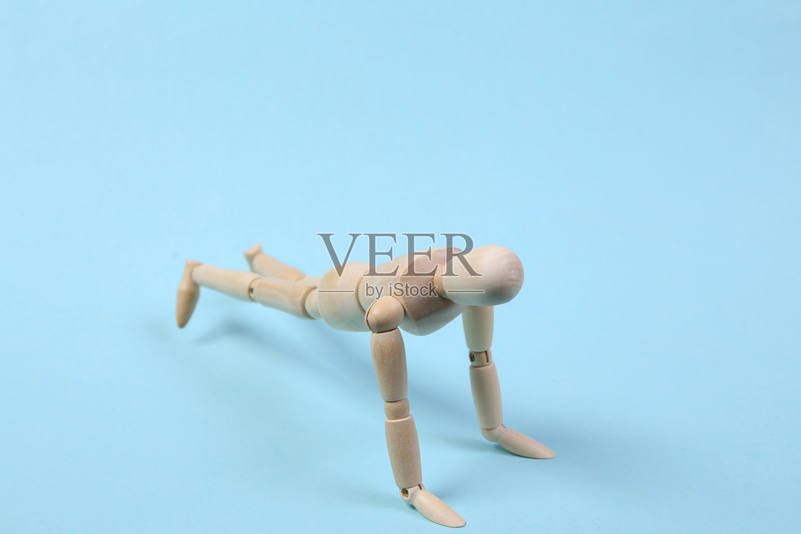 蓝色背景上的木偶戏俯卧撑。体育的概念照片摄影图片