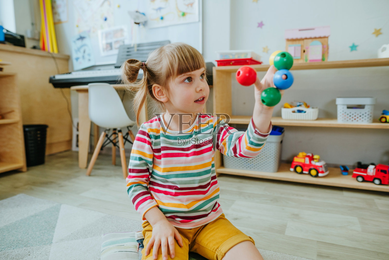 学前班的学生们坐在地板上整理木制的几何形状照片摄影图片