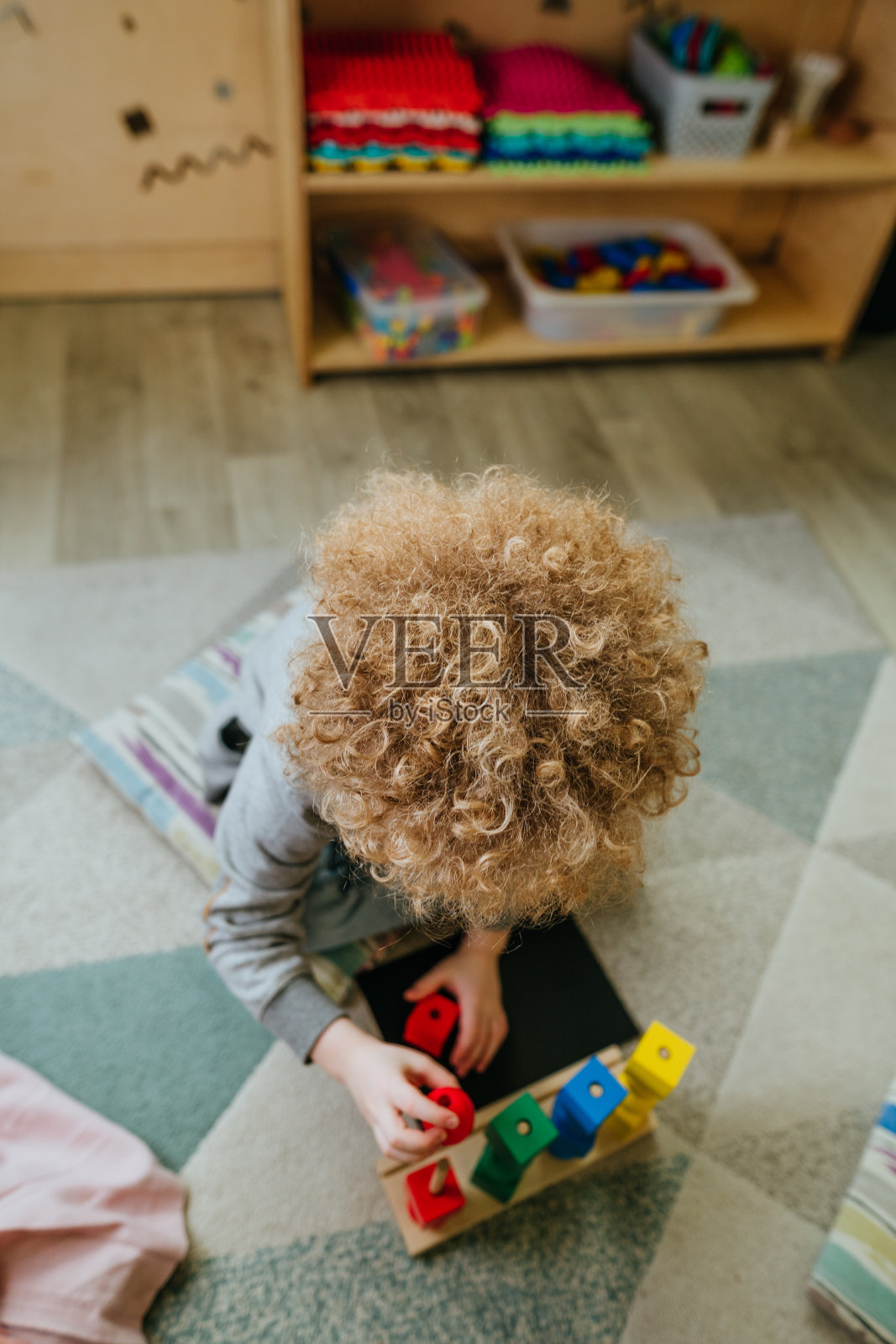 学前班的学生们坐在地板上整理木制的几何形状照片摄影图片