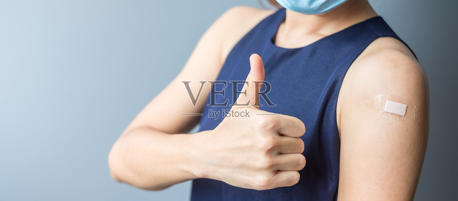 一名快乐的女性在接种新冠疫苗后，露出了绑着绷带的拇指。疫苗接种、群体免疫、副作用、效率、疫苗护照和冠状病毒大流行照片摄影图片
