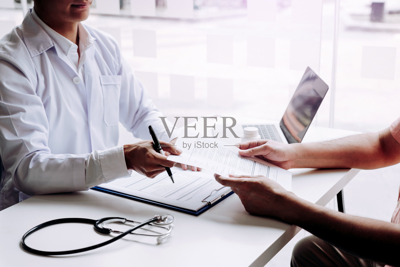 医生用便利贴提交病人记录，并与病人谈论药物和治疗。照片摄影图片