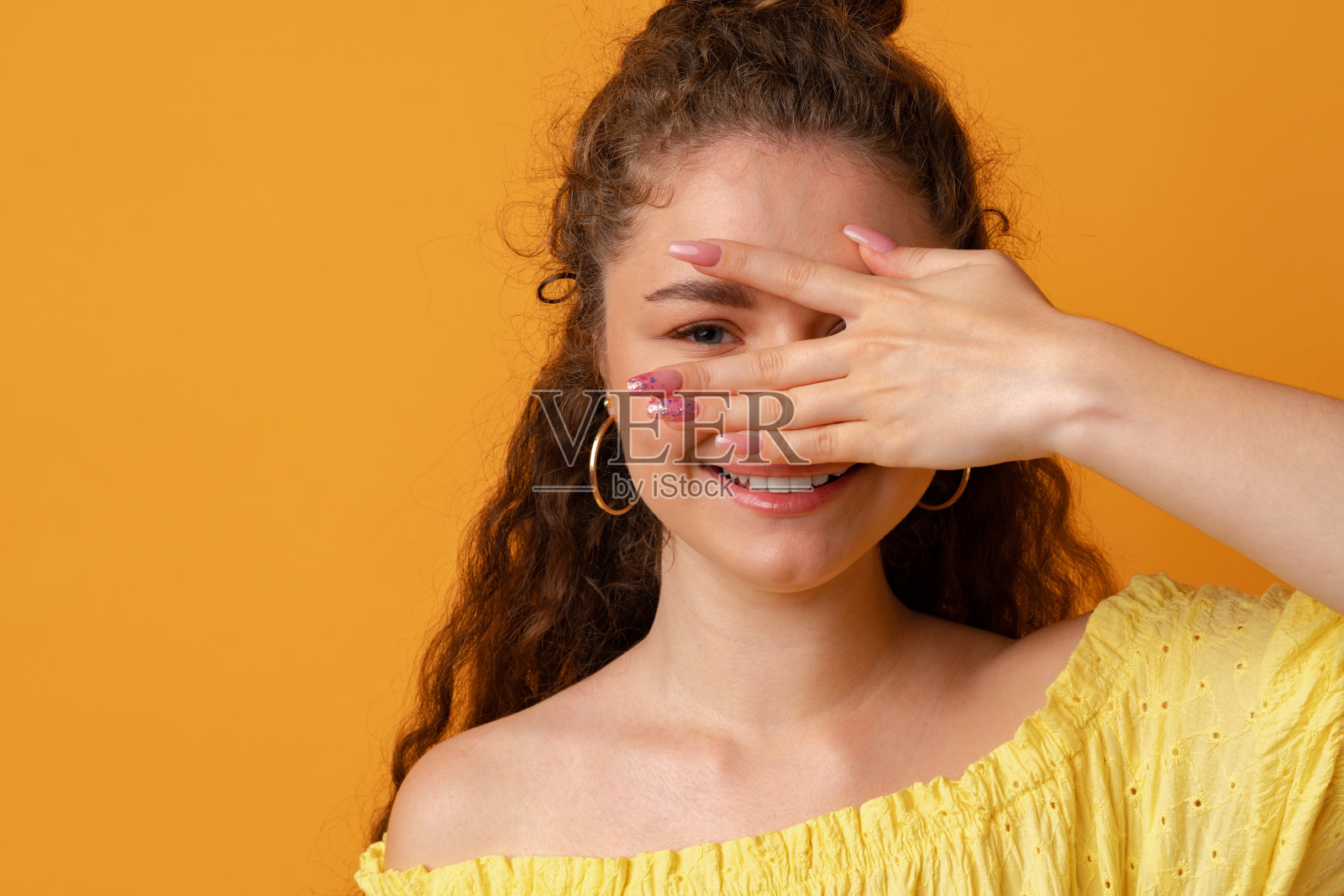 年轻女子微笑着，用手捂住脸，摄影棚里的肖像照片摄影图片