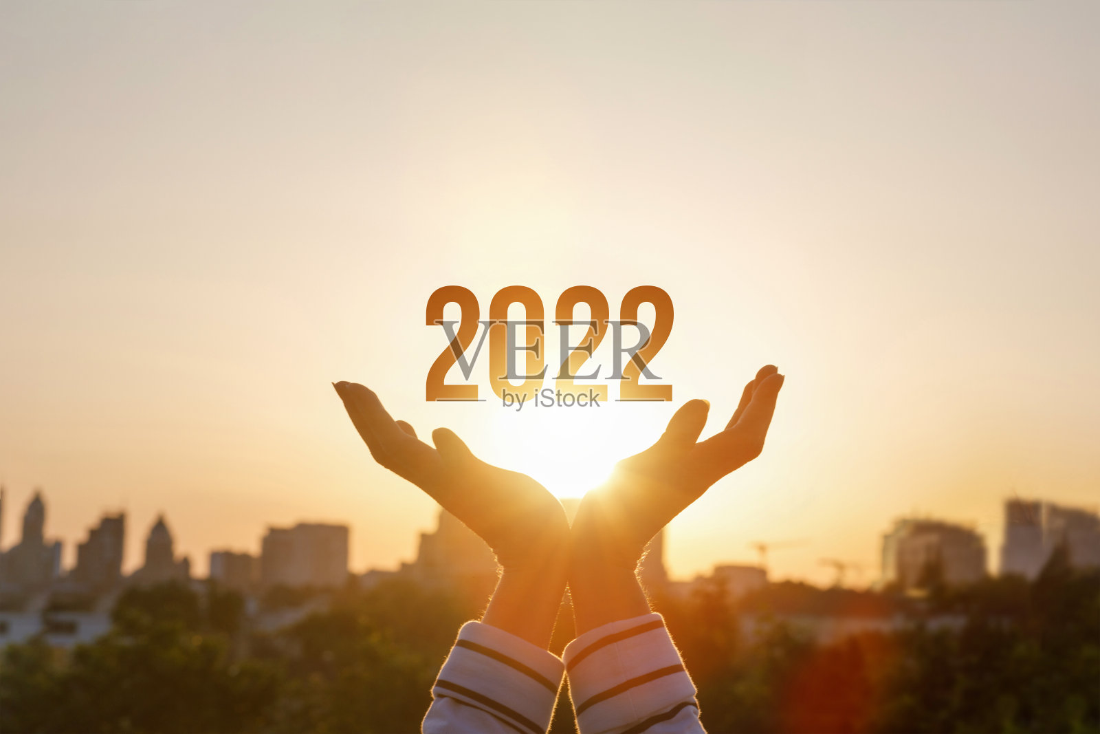 2022年是在阳光明媚的日落背景下由人手支持的。照片摄影图片