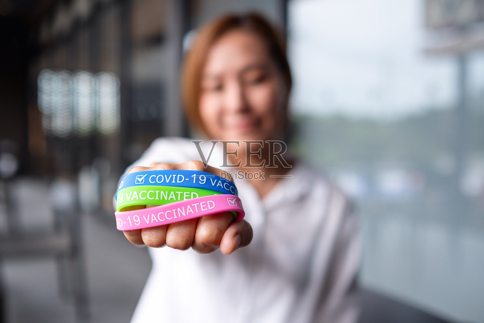一名妇女戴着彩色的Covid-19疫苗手环，展示保健概念照片摄影图片