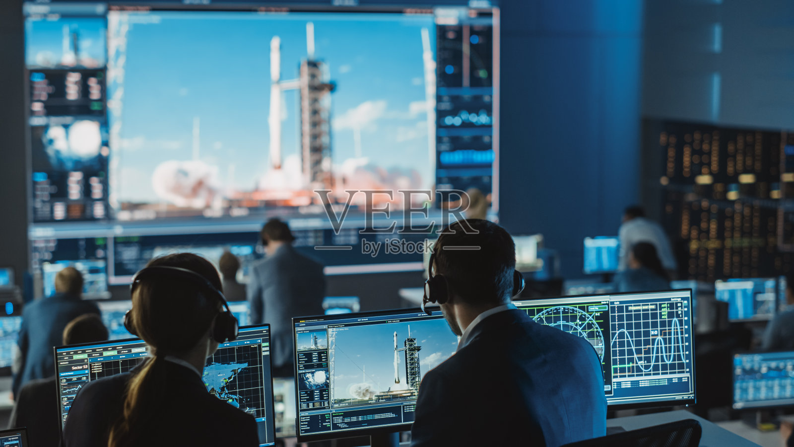 任务控制中心人员见证航天火箭发射成功。飞行控制人员坐在电脑显示器前，监控机组任务。照片摄影图片