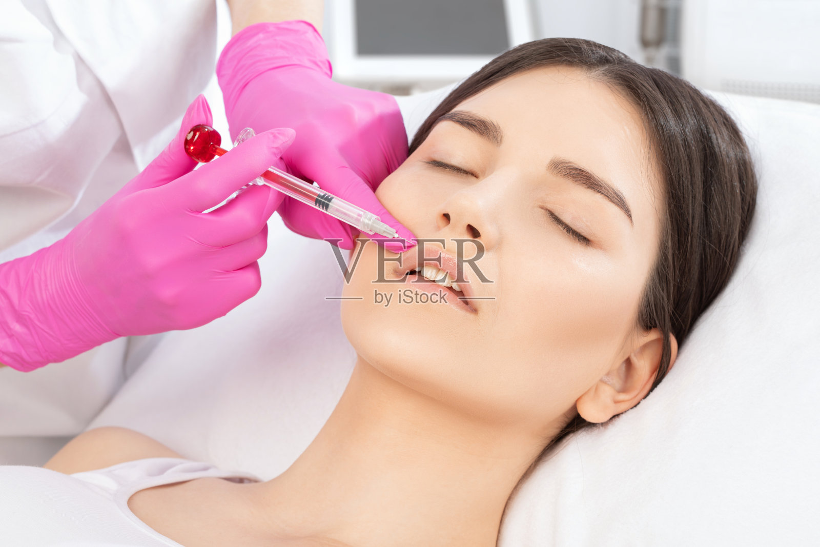 美容师为一个美丽的女人做嘴唇增强和抗皱纹注射。美容院的女性美容。照片摄影图片