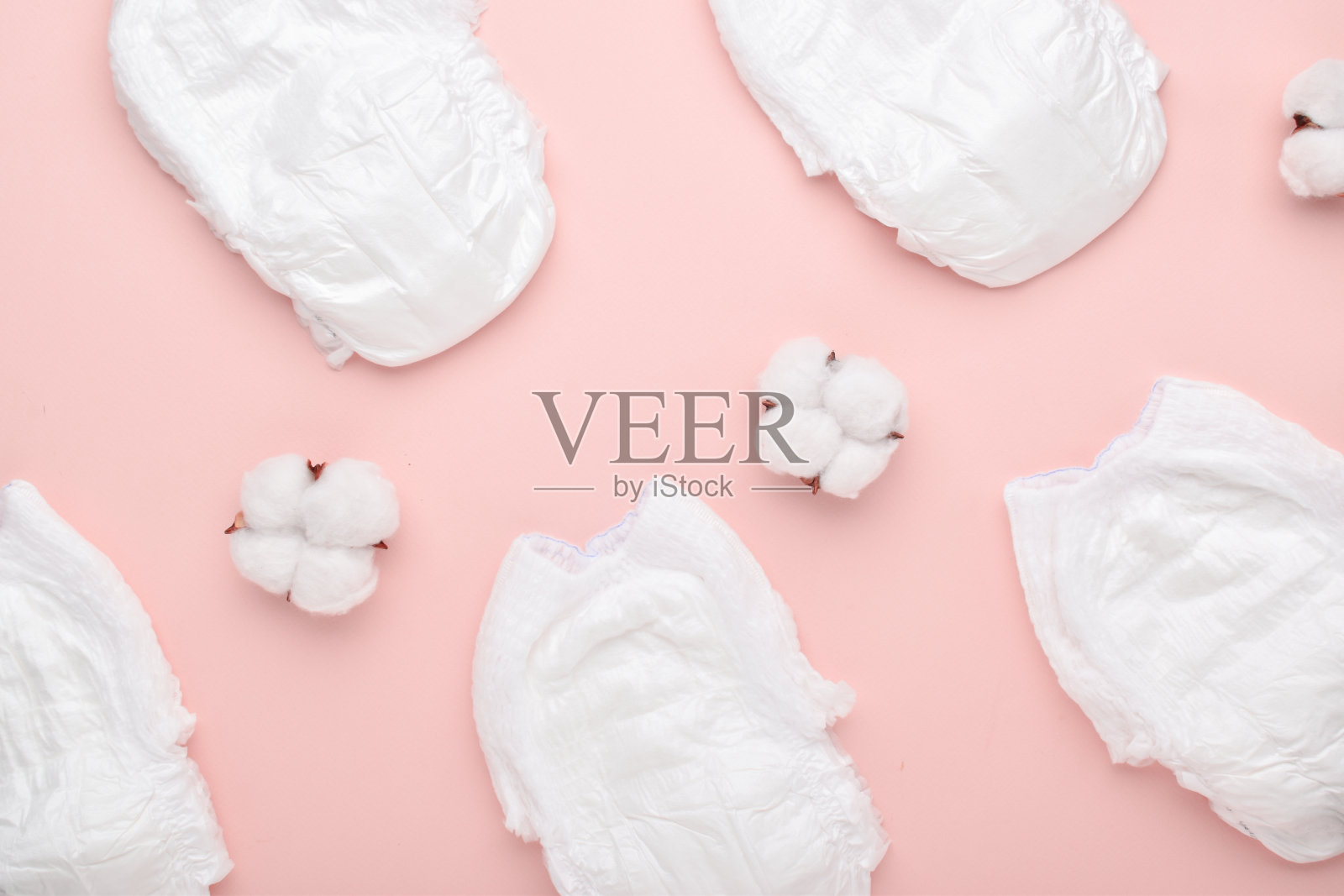 尿布的背景内裤和棉花花在粉红色的背景。他脸朝下躺着。照片摄影图片