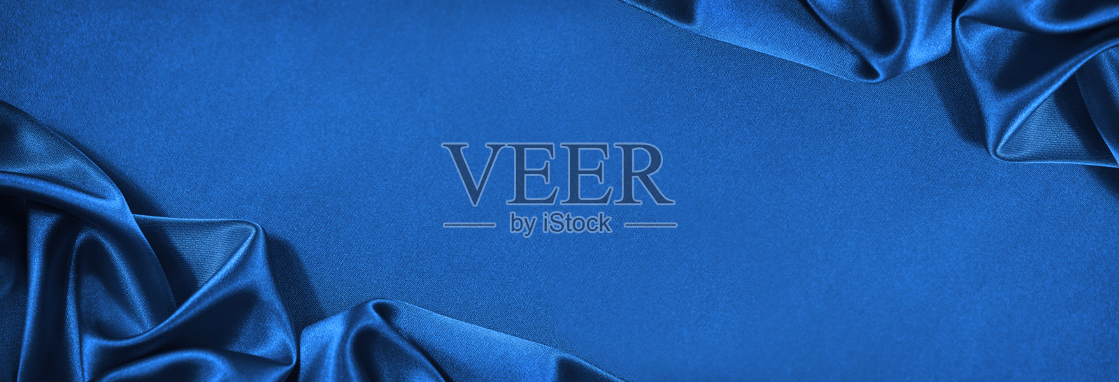 美丽的蓝色绸缎背景。波浪柔软的褶皱。优雅的面料背景与复制空间的设计。网页横幅。照片摄影图片