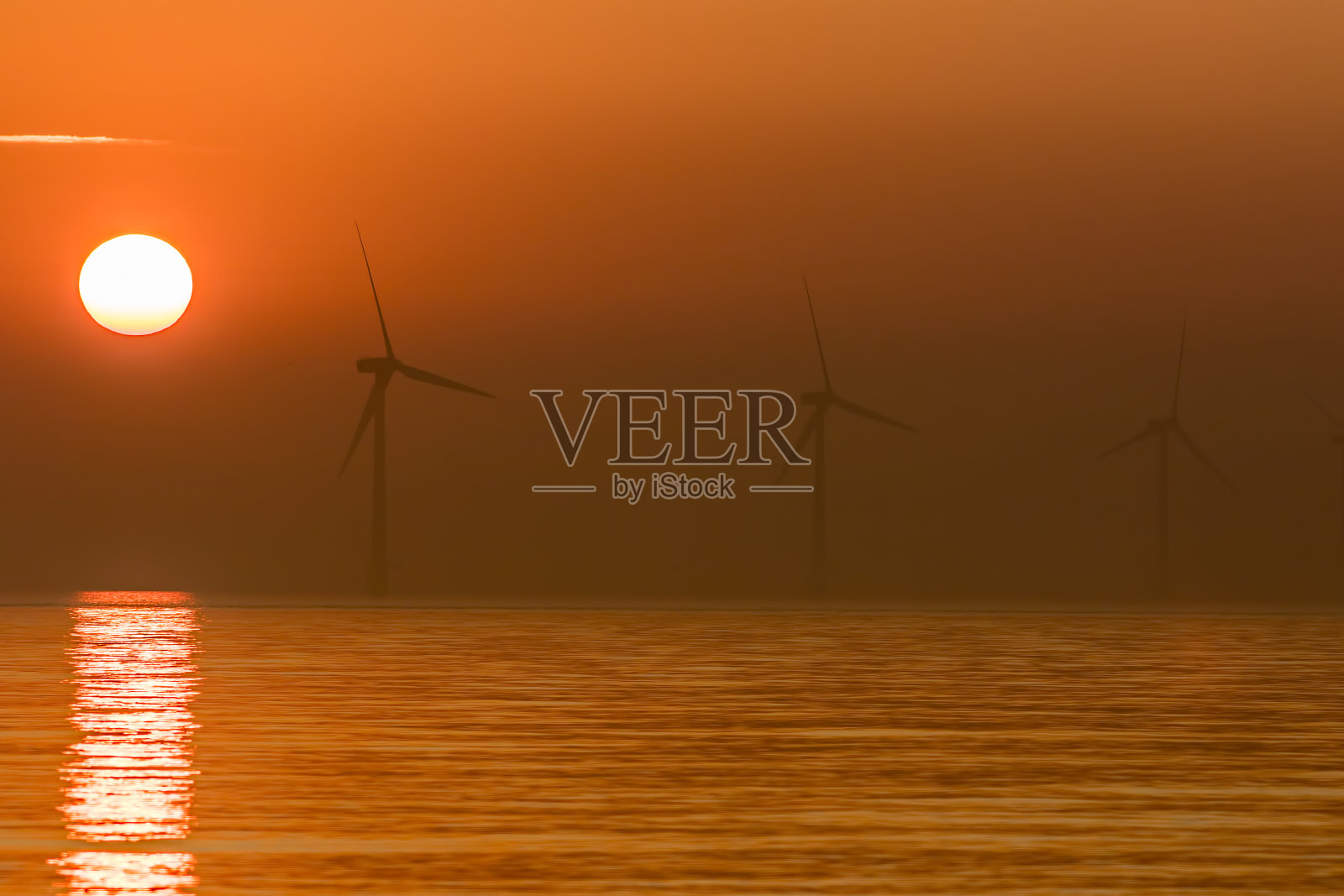 太阳能和风能。日出时的海上风力发电机。照片摄影图片