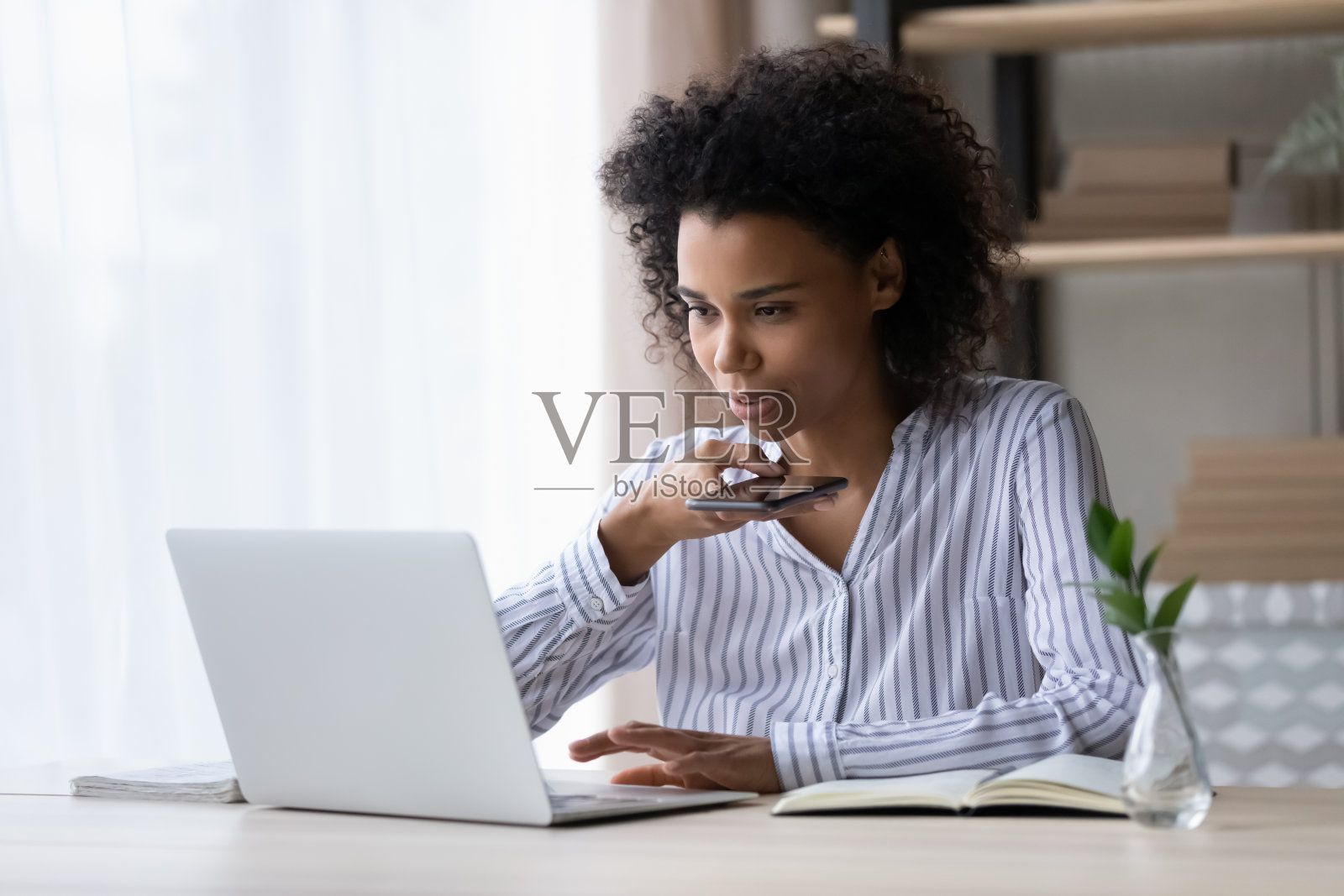 年轻的少数民族女商人用手提电脑和手机通话照片摄影图片