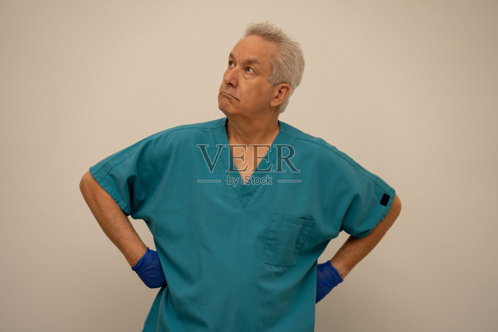 男护士，双手叉腰，目光向上，远离镜头照片摄影图片