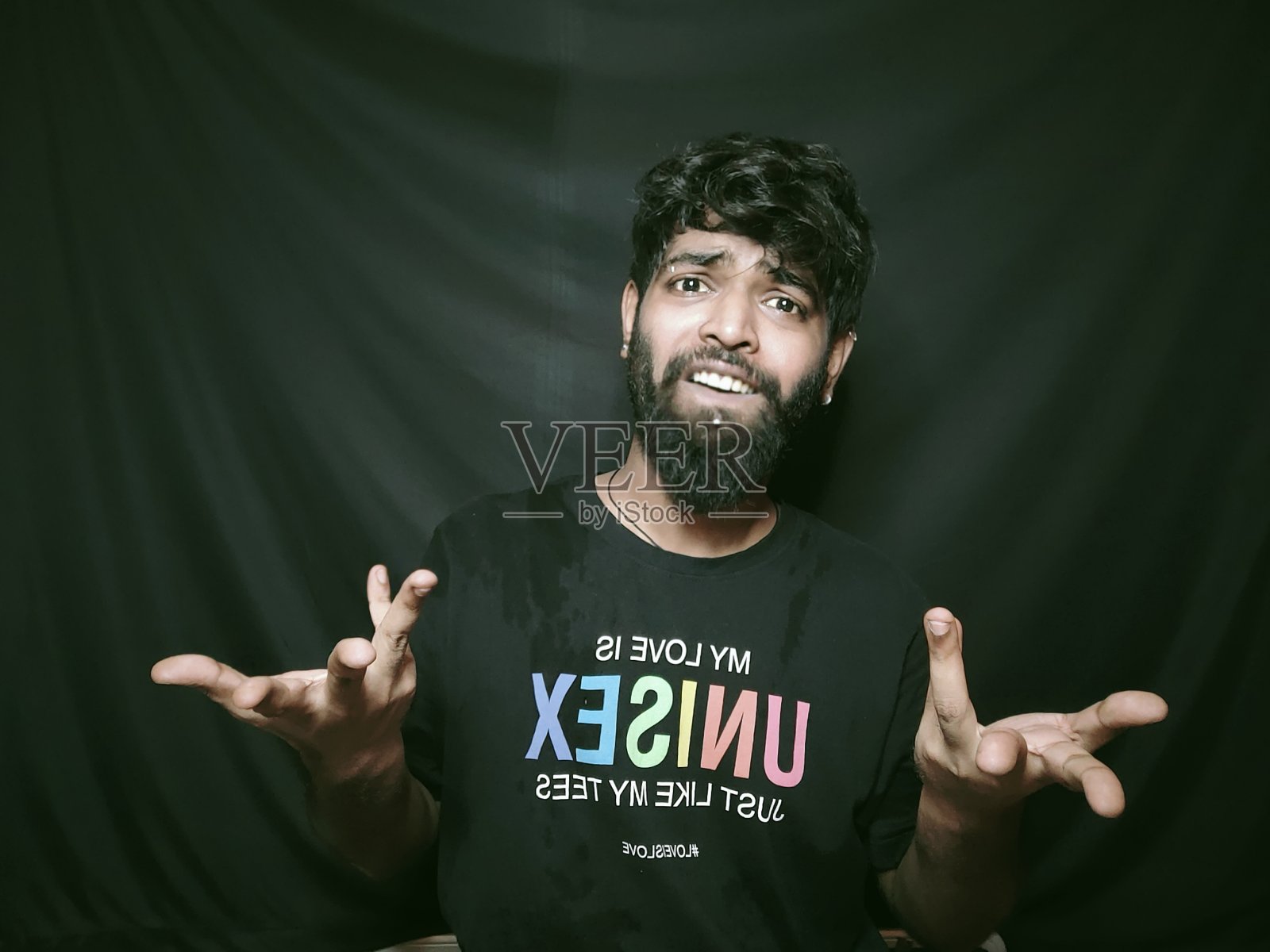 愤怒的胡须印度男模特，黑色t恤和灰色背景照片摄影图片